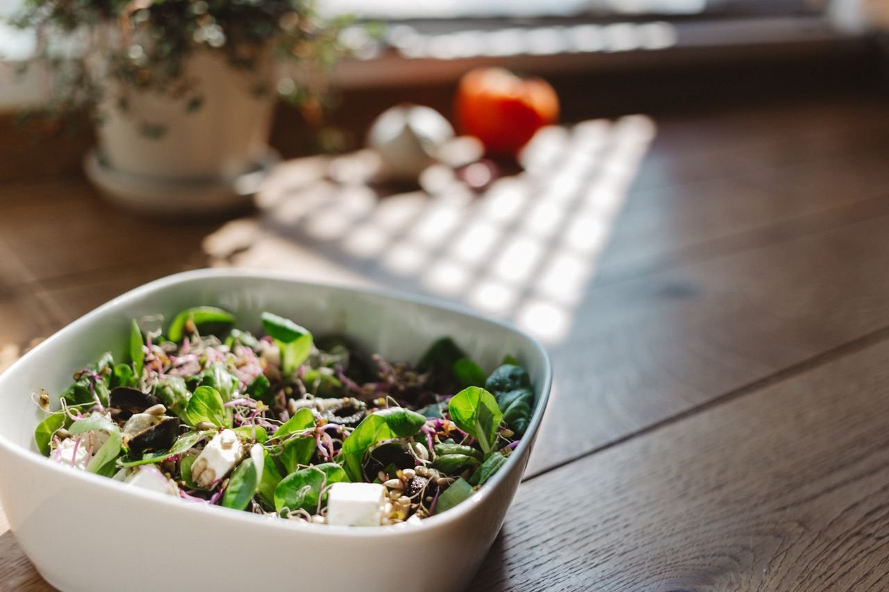 A vibrant and healthy bowl of tofu salad with fresh greens, captured in natural light on a wooden table.